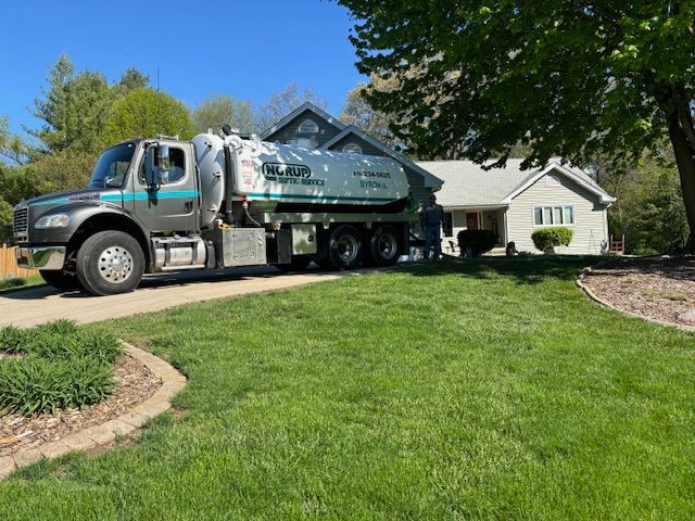 A vacuum truck is parked in front of a house.