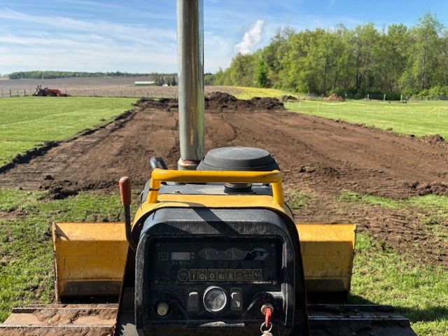 A yellow bulldozer is sitting on top of a dirt field.