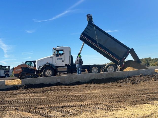A dump truck is being loaded with dirt on a construction site.