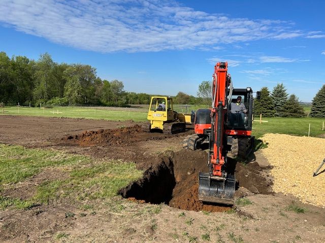 An excavator is digging a hole in the ground in a field.