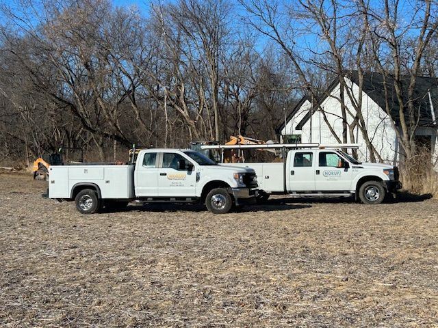 Two white trucks are parked next to each other in a field.