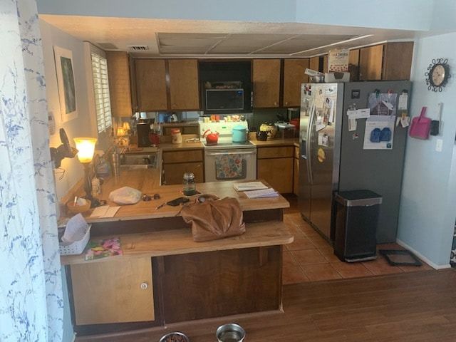 A kitchen with wooden cabinets and a stainless steel refrigerator