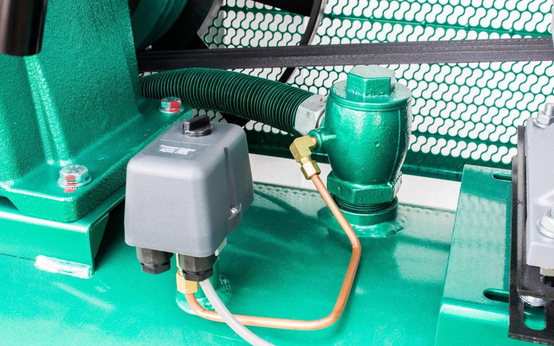 Green air compressor components: pressure switch, tank, tubing, and belt.