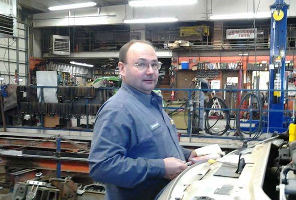 A man in a blue shirt is standing in a factory