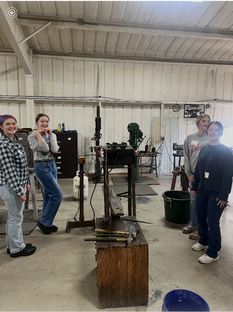 Group of people in a workshop setting, smiling and looking towards the camera.