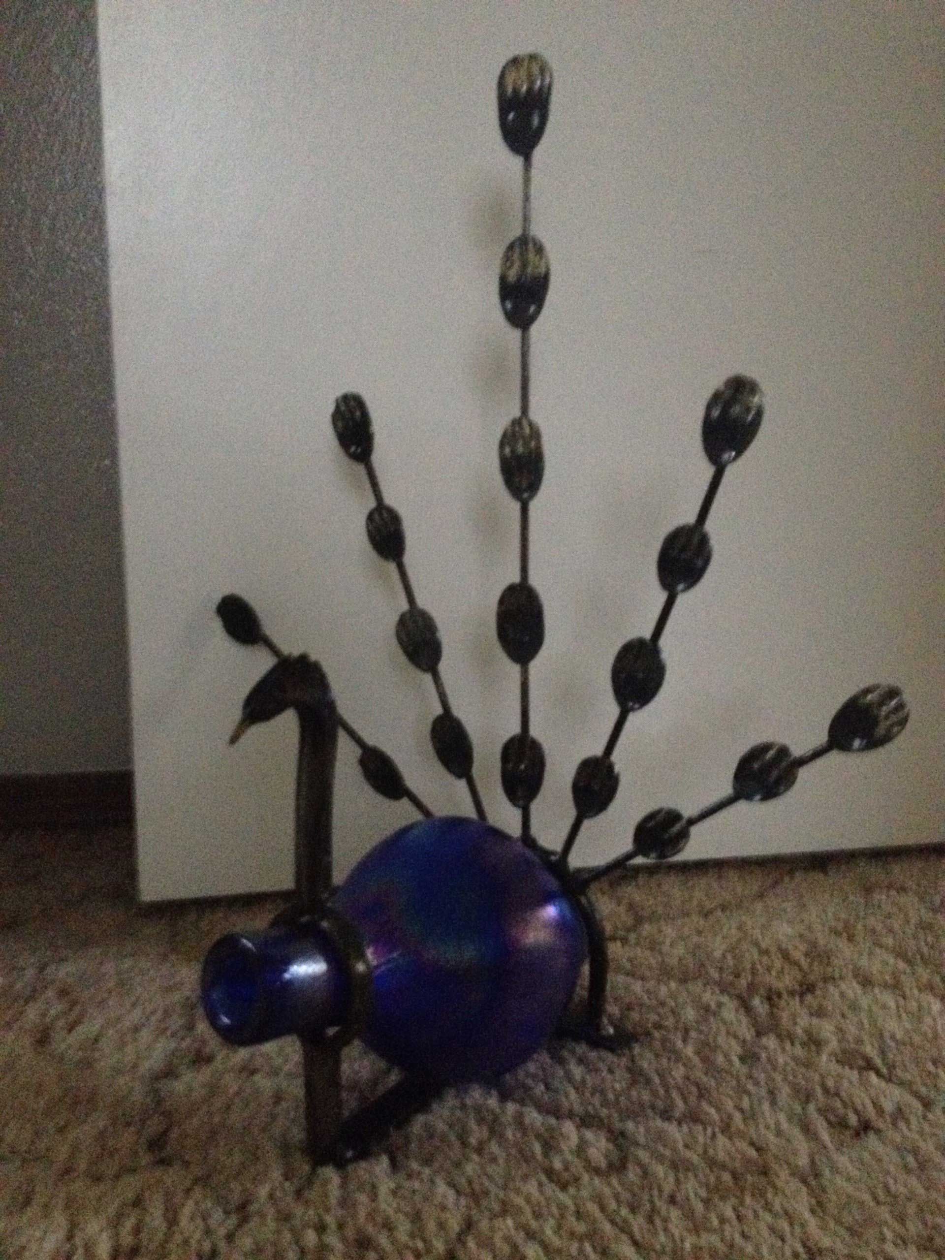 Blue glass peacock sculpture with metal tail feathers.
