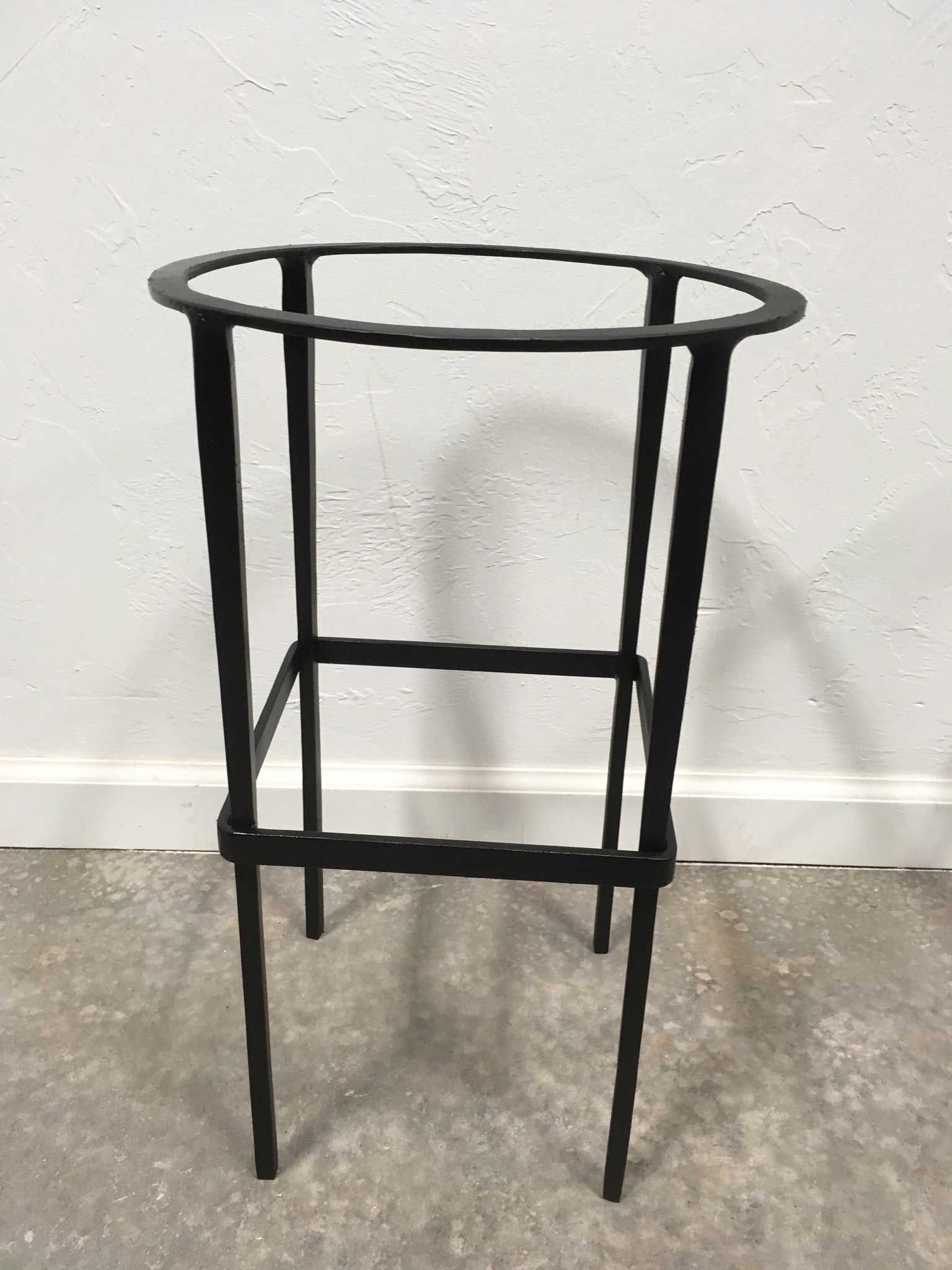 Black metal plant stand with a circular top and a rectangular support.