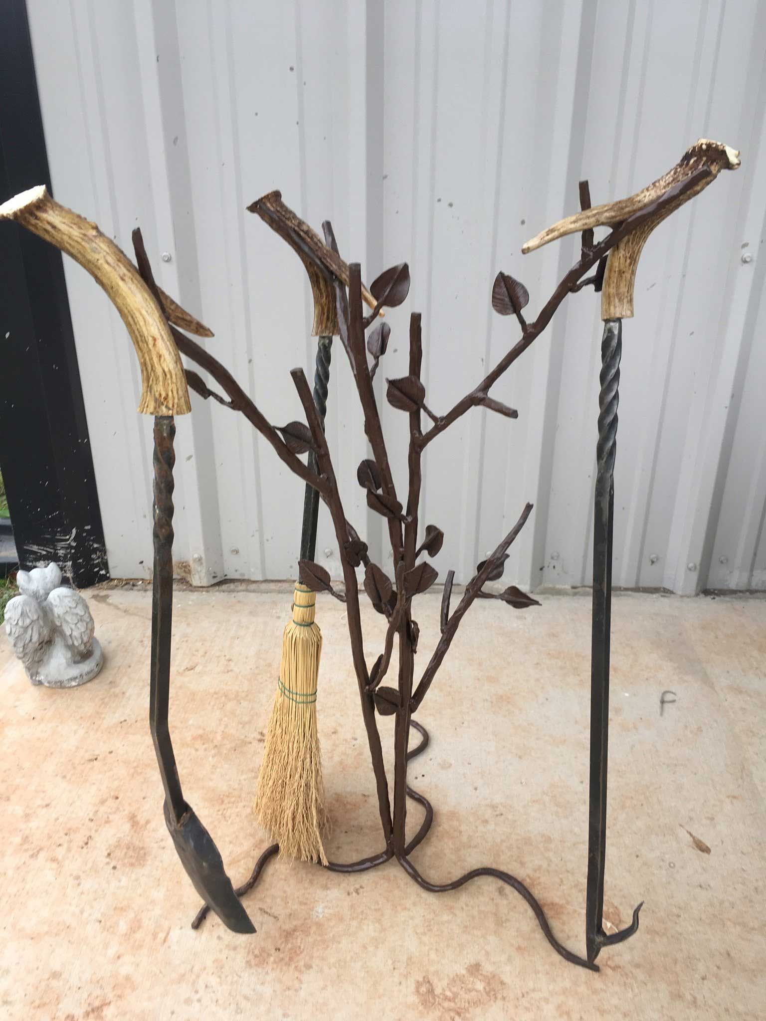 Metal fireplace tools with antler handles and leaf detail on a stand.