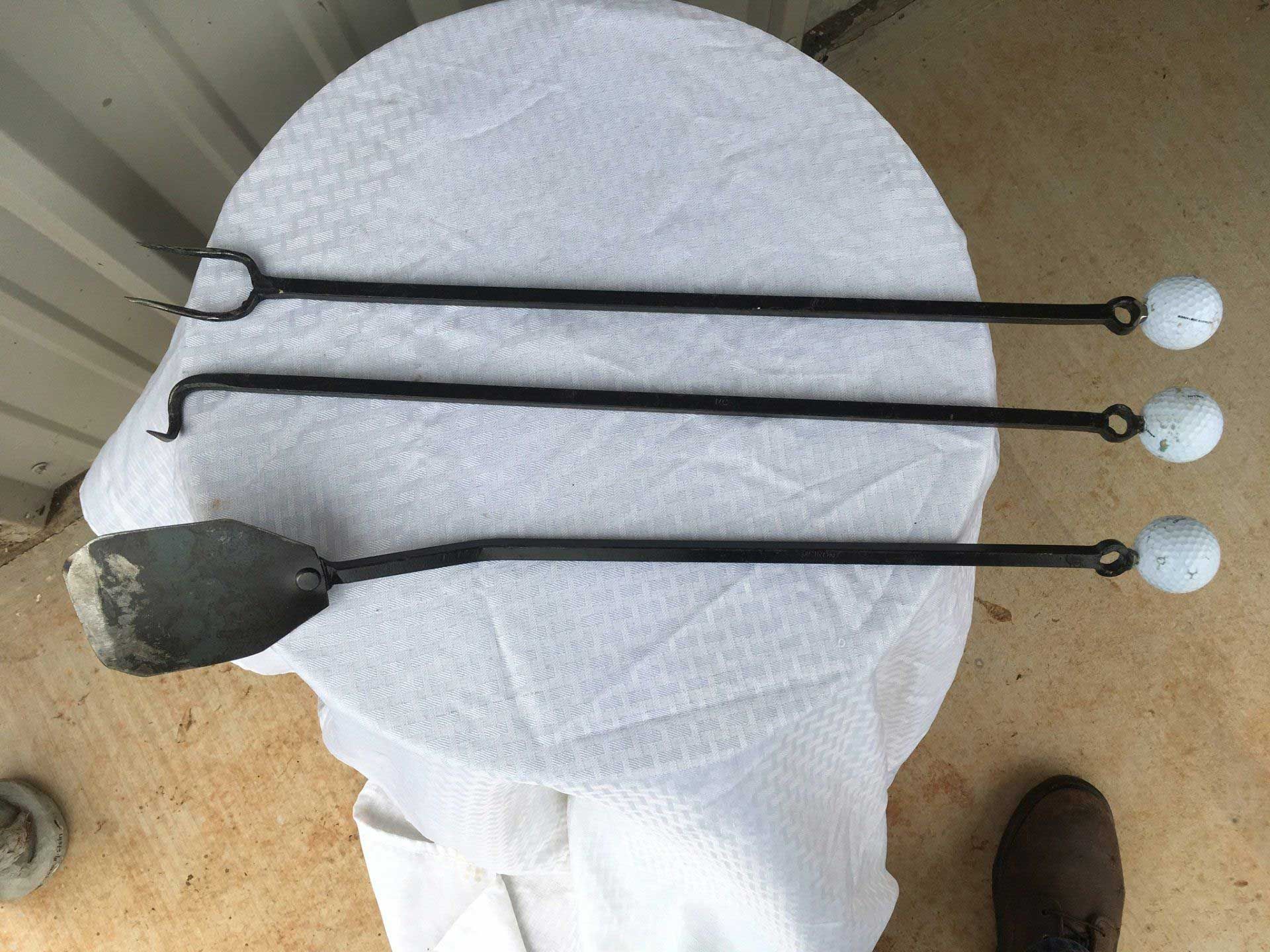Three black fireplace tools with white knob handles on a white cloth.