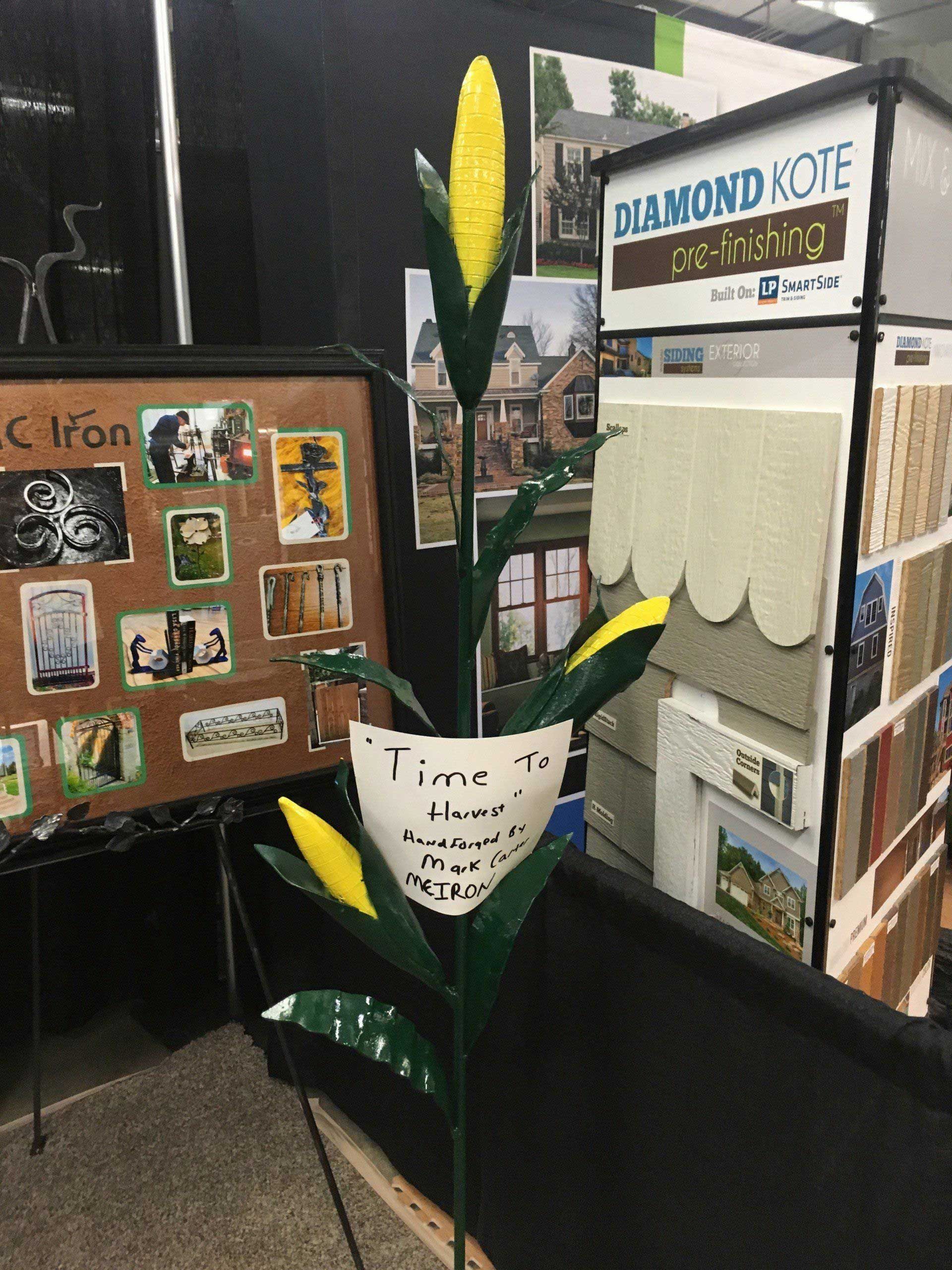 Metal corn stalk sculpture at an event, with sign 