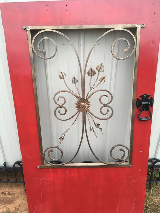 Red door with ornate gold metal screen, black door knocker.