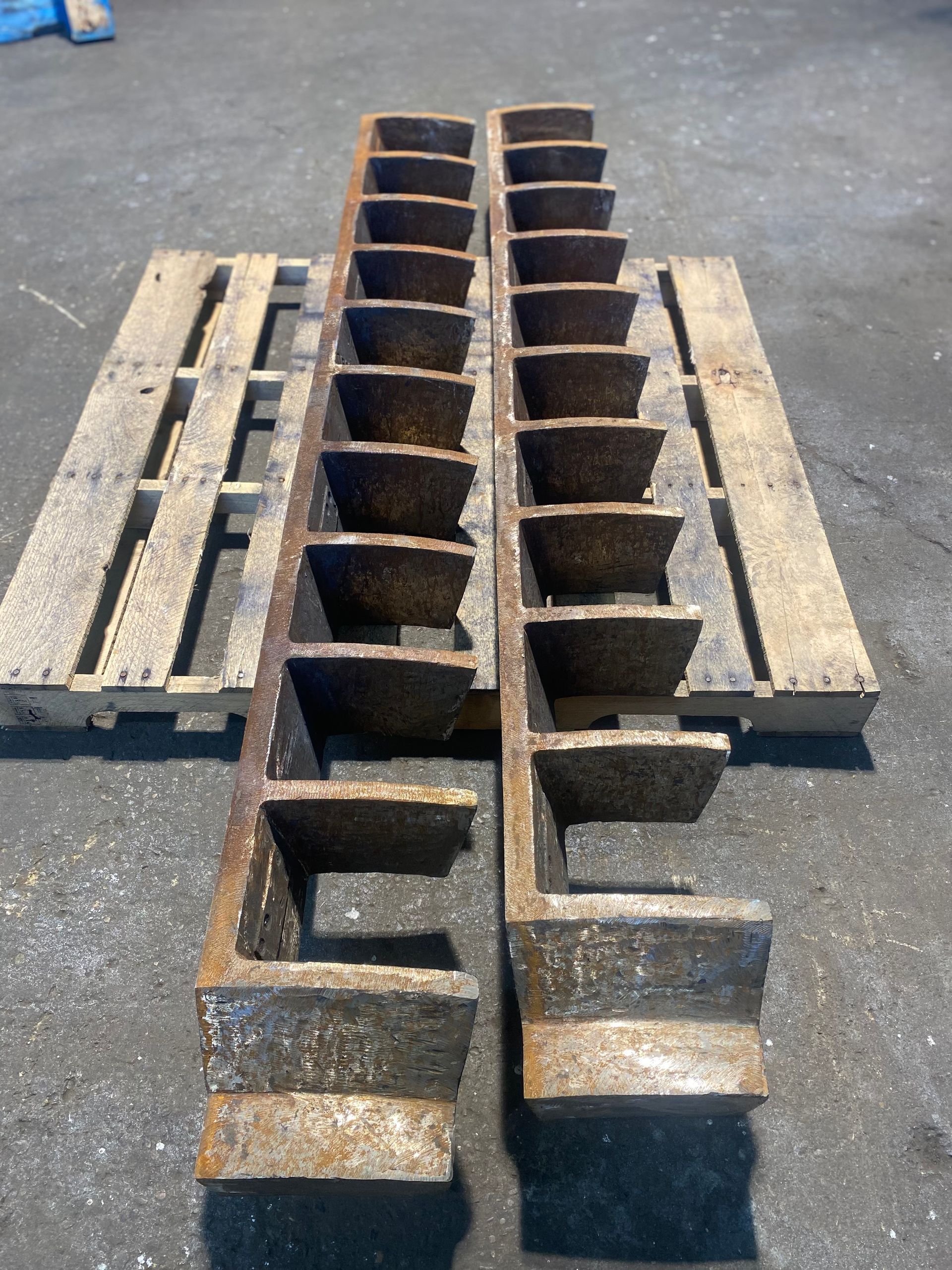 Two rusty, rectangular metal grates on wooden pallets, angled steps visible.