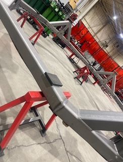 Metal frame supported by red sawhorse stands inside a workshop.
