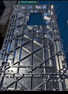 Close-up of a complex aluminum component with geometric patterns, likely machined for technological applications.