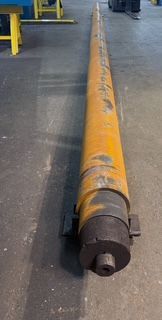 Long, cylindrical, orange metal object on a gray floor, likely industrial equipment.