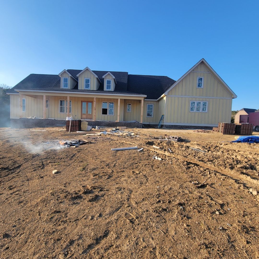 Two construction workers are installing siding on a house with a porch.
