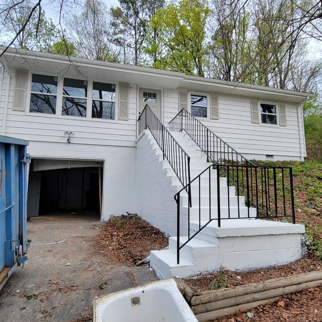A white shed with a brown porch overlooking a pool, set in a backyard.