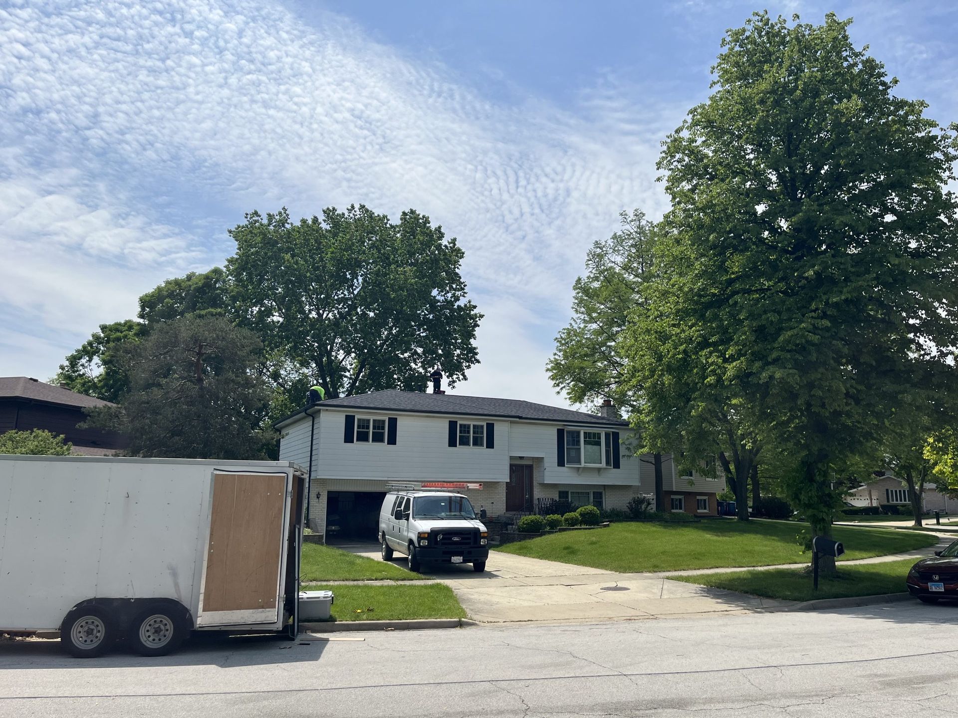 A white trailer is parked in front of a house