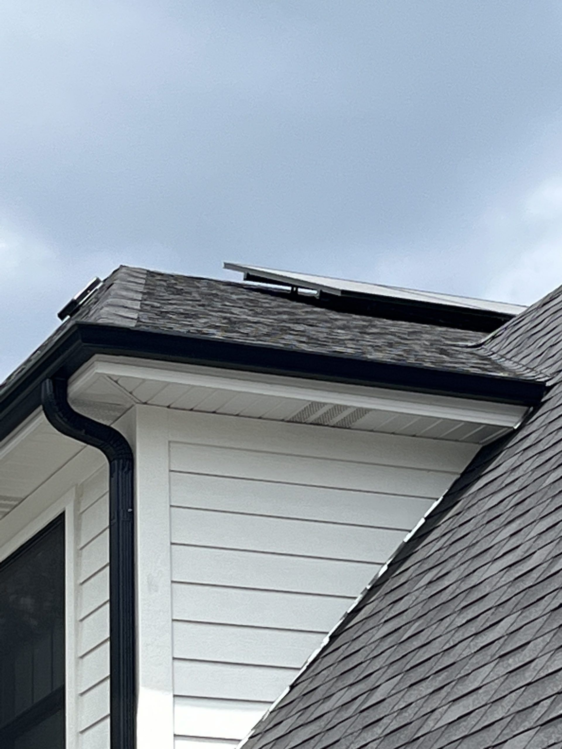 A white house with a gray roof and a black gutter.