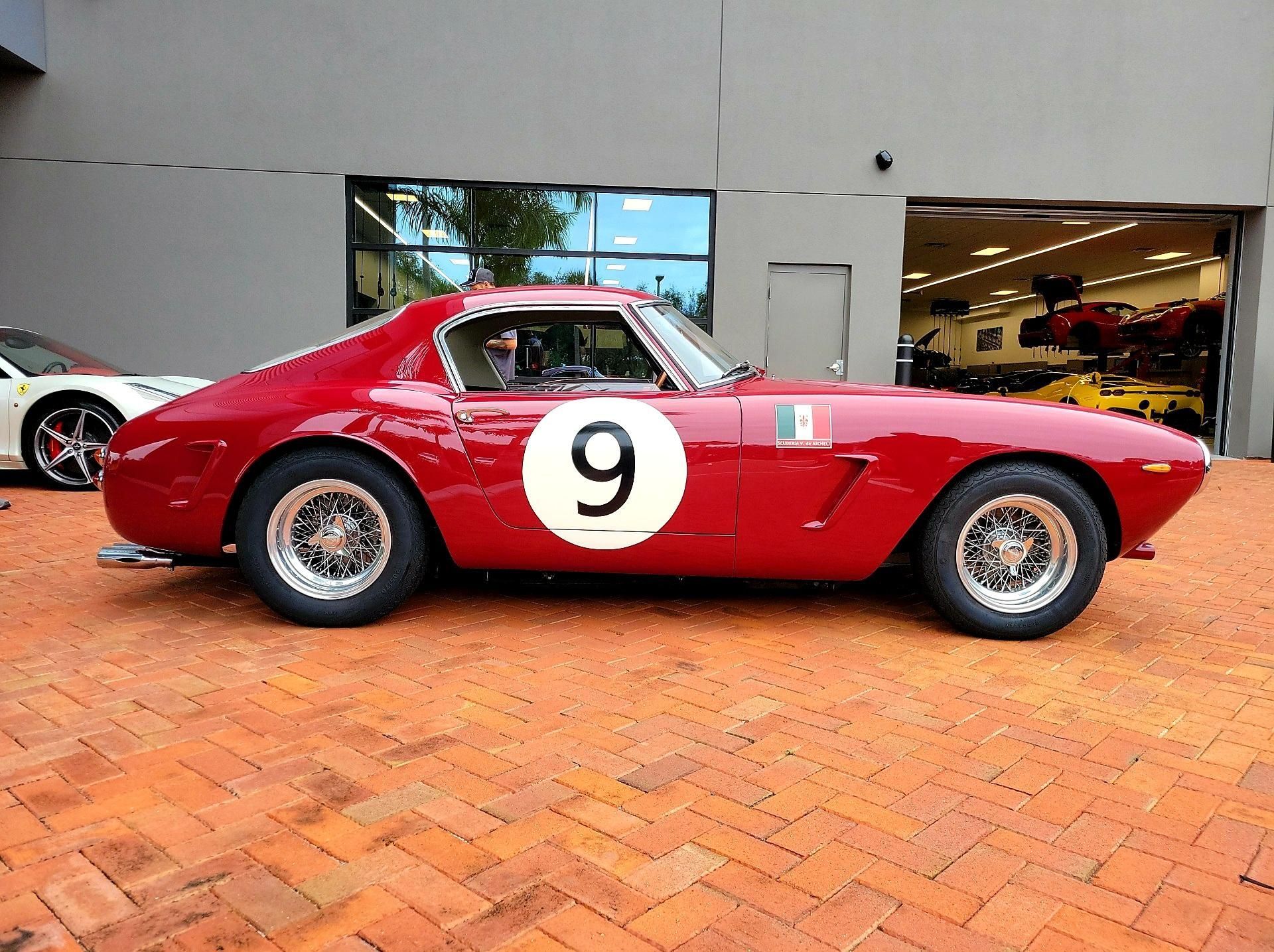 A red race car with the number 9 on the side is parked in front of a building.