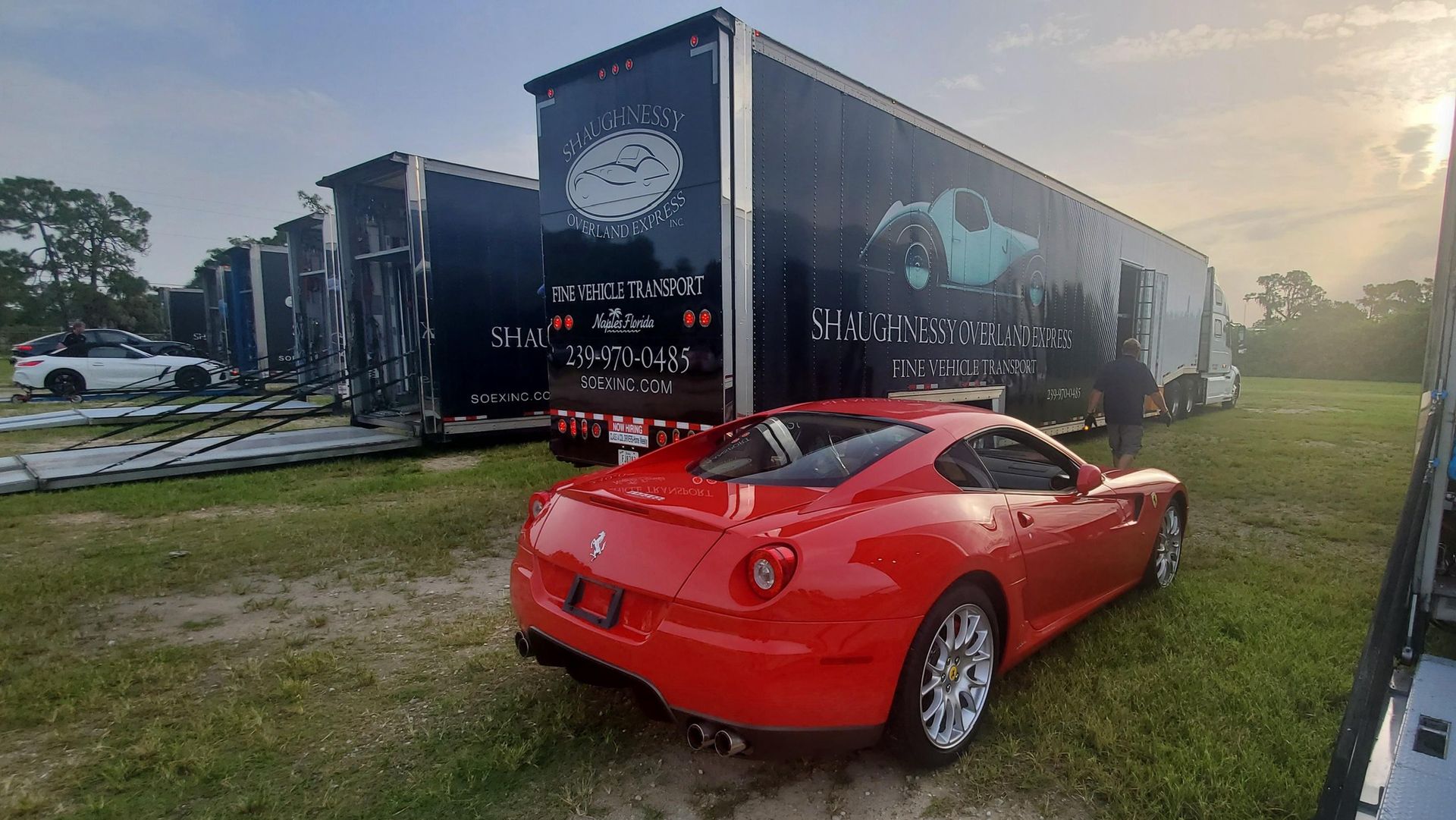 A red sports car is parked in front of a trailer.