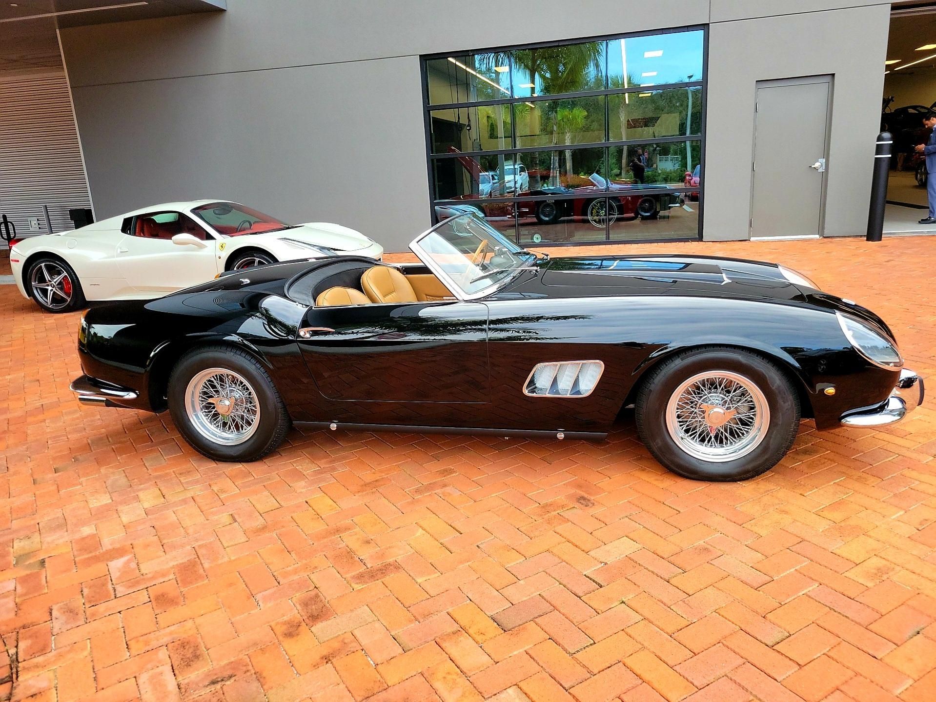 A black sports car is parked next to a white sports car in front of a building.