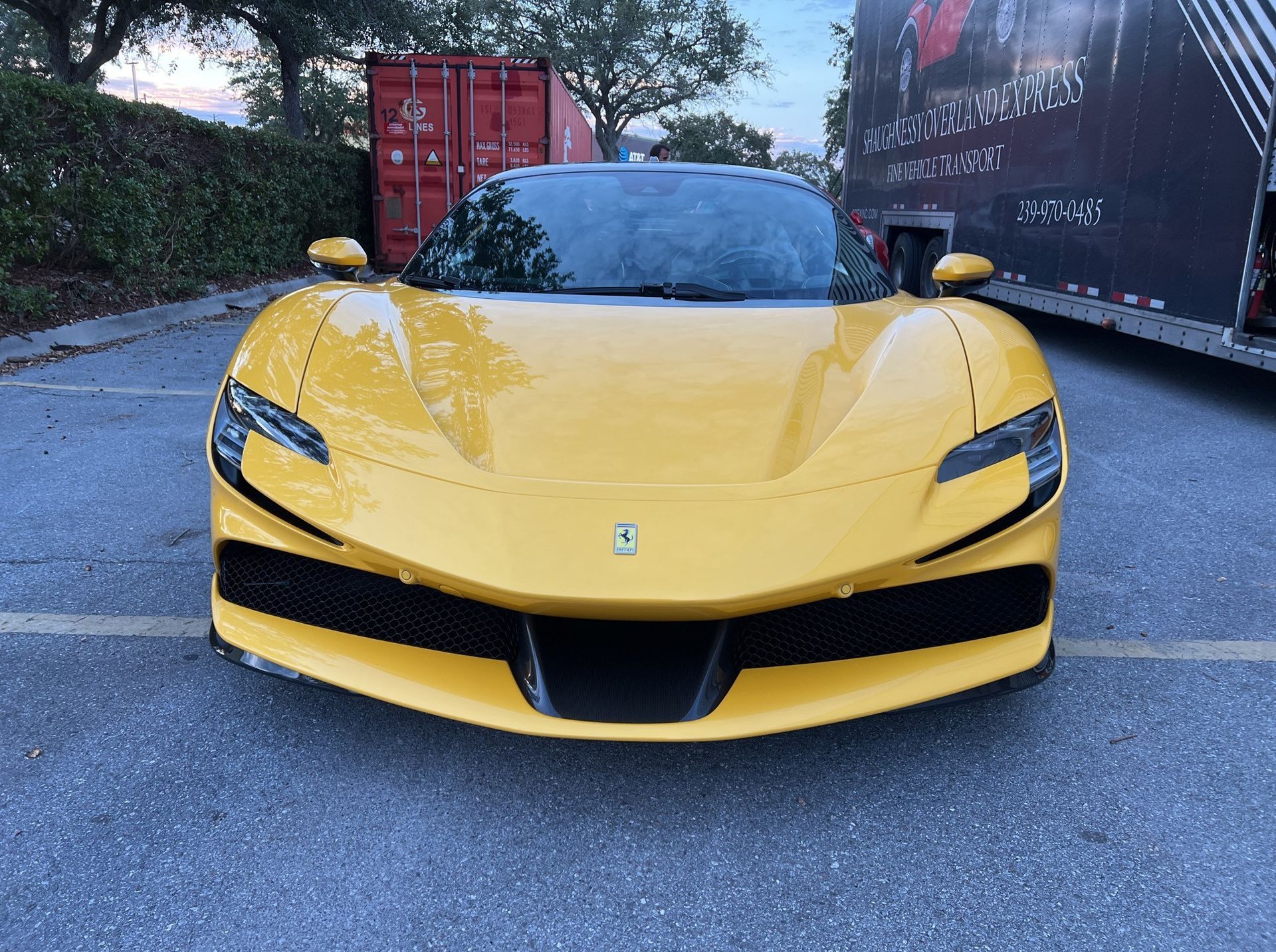 A yellow ferrari sports car is parked in a parking lot.