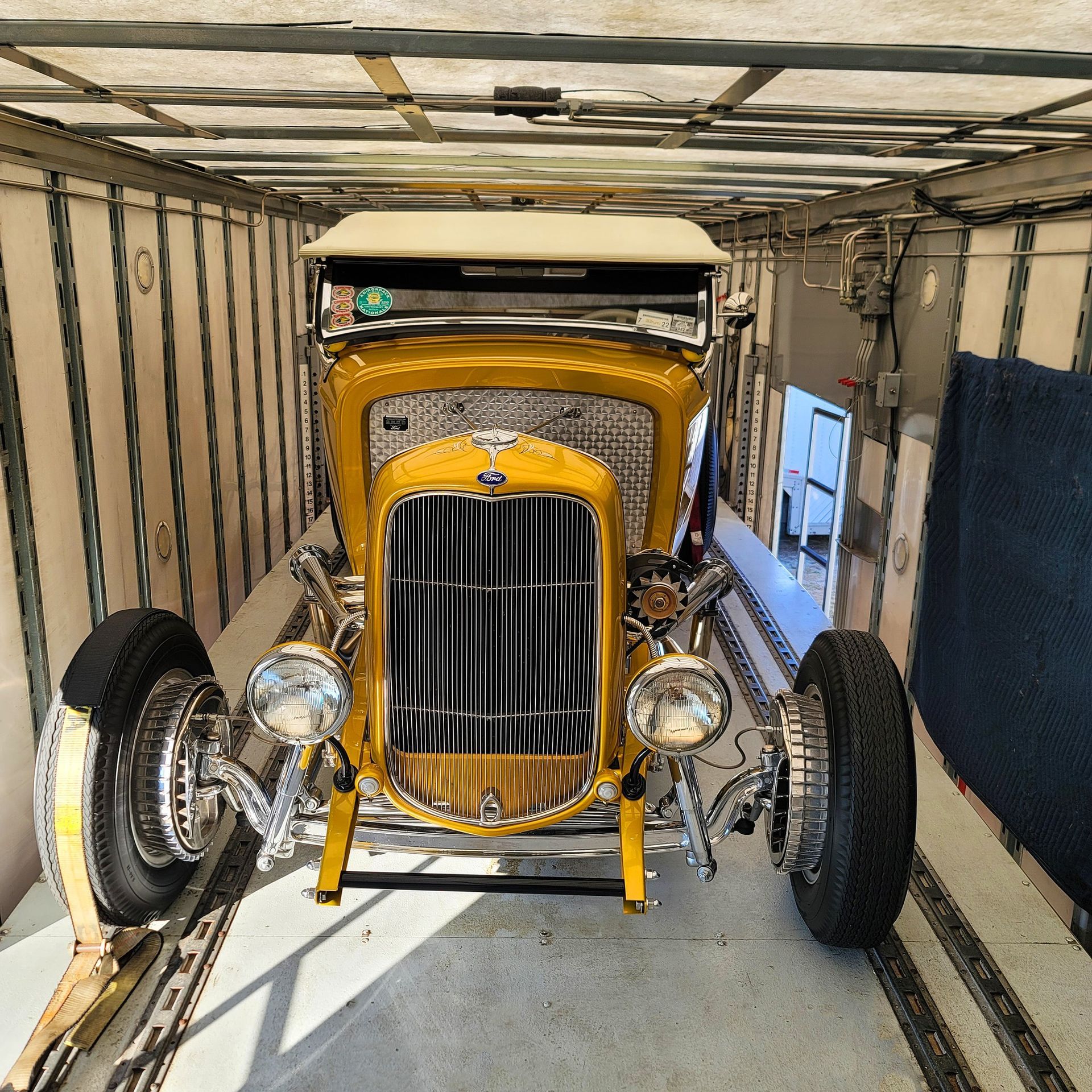 A yellow car is parked inside of a trailer
