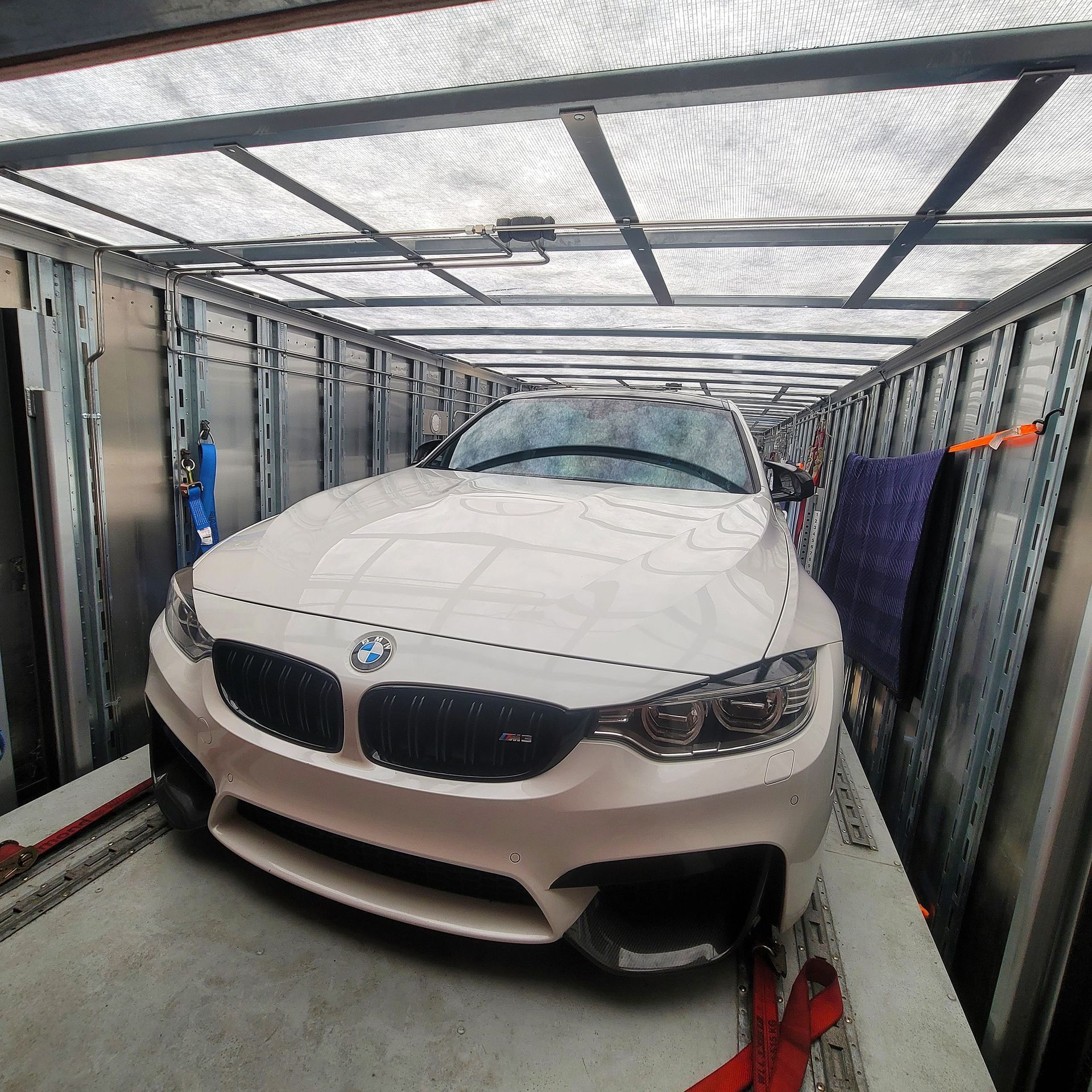 A white bmw is parked inside of a shipping container
