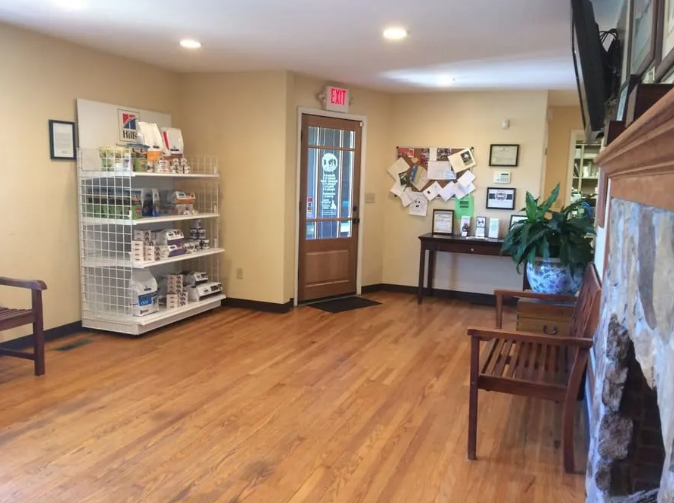 Waiting room with wooden floor, benches, and a product display. A door leads outside.