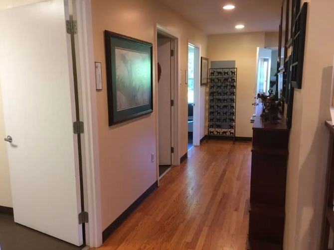 Hallway with wood floor, doors, artwork, and a display case.
