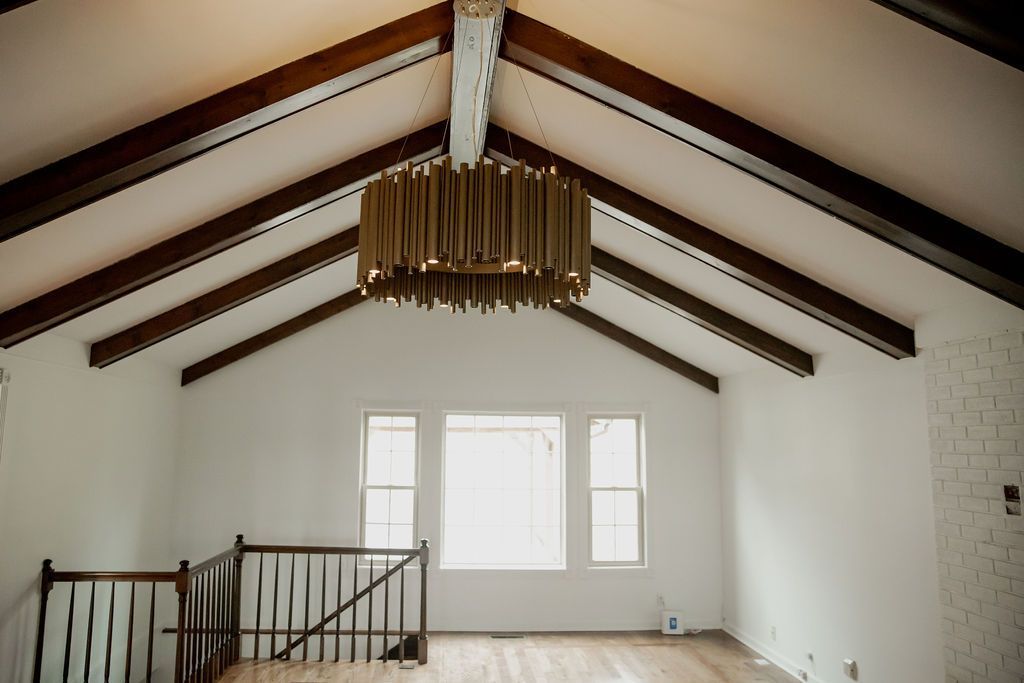 An empty room with a vaulted ceiling and a chandelier hanging from the ceiling.