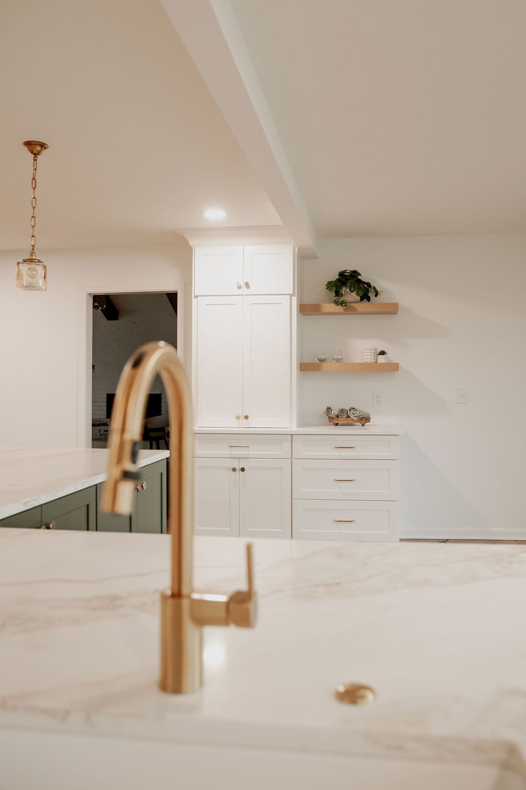 A kitchen sink with a gold faucet and white counter tops.