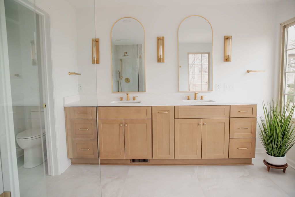 A bathroom with two sinks , two mirrors and a toilet.
