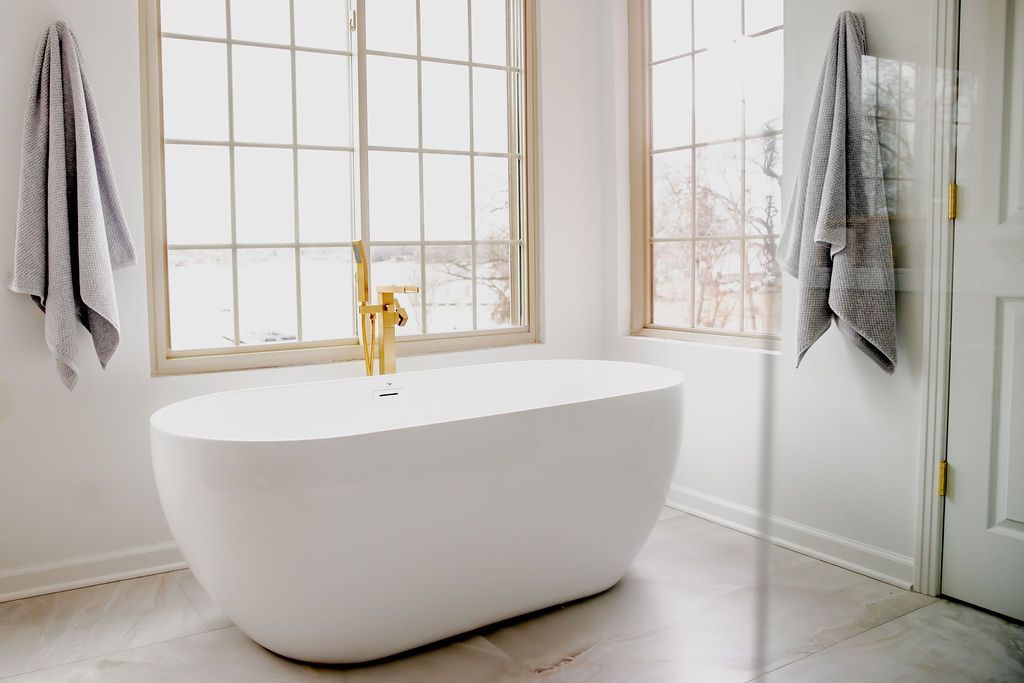 There is a bathtub in the bathroom next to a window.