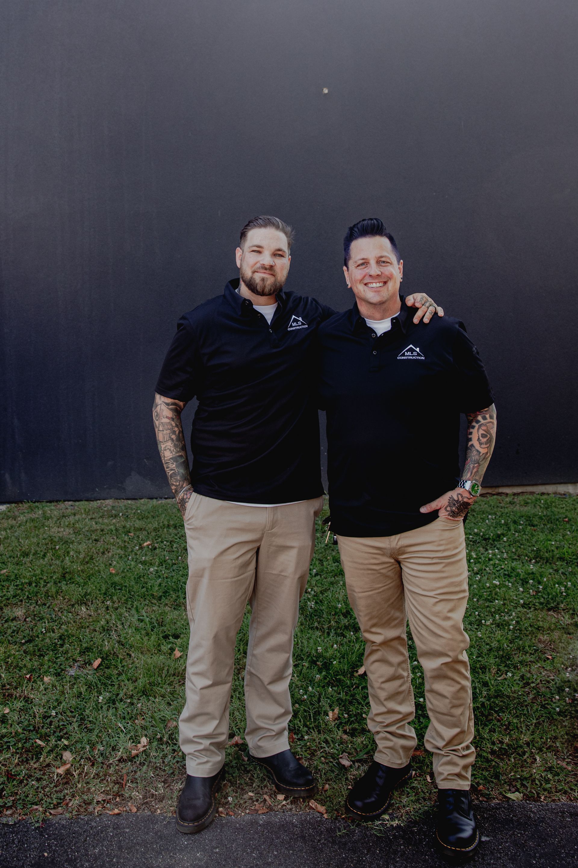 Two men are standing next to each other in front of a building.