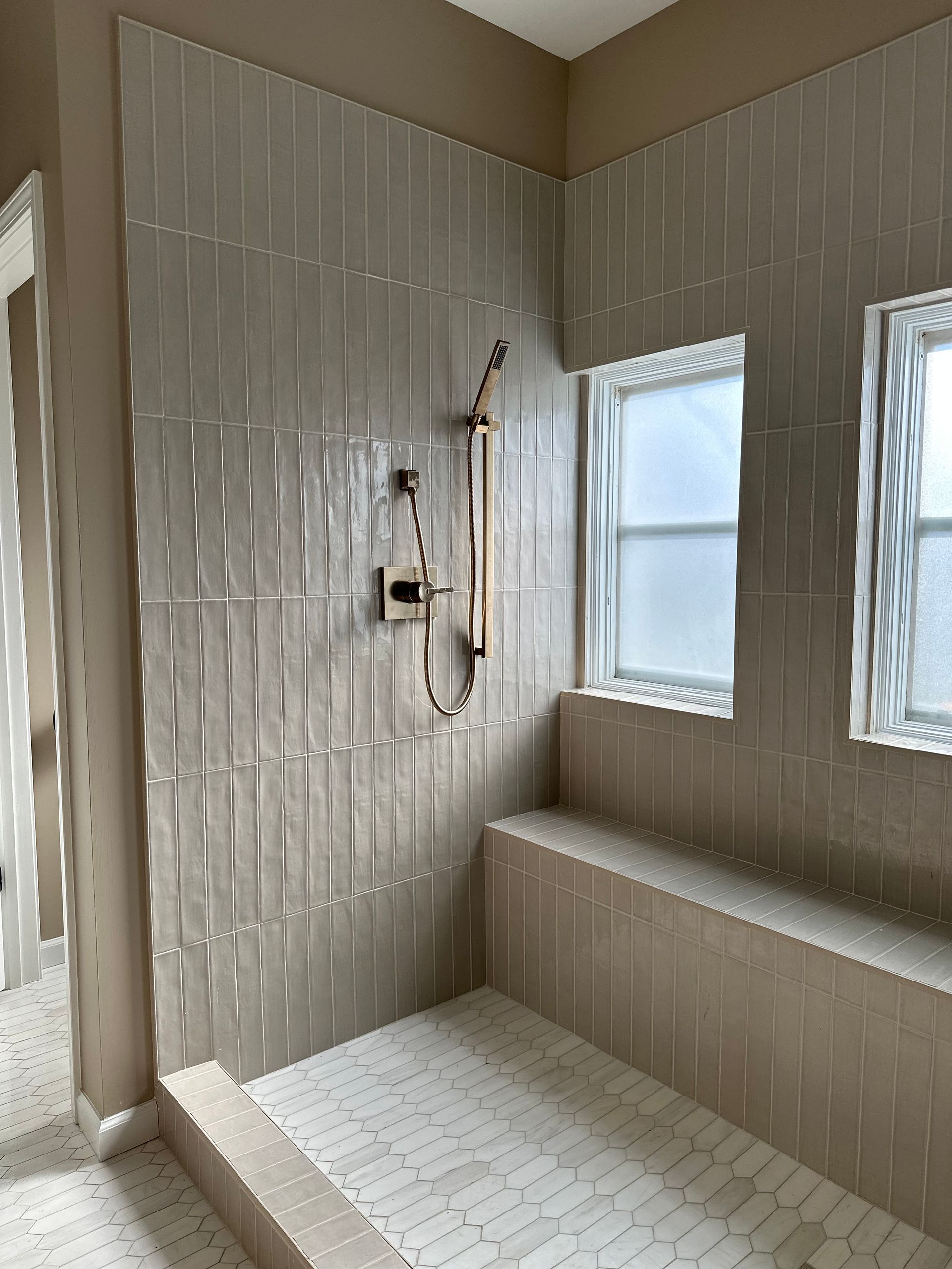 A bathroom with a walk in shower and a window.