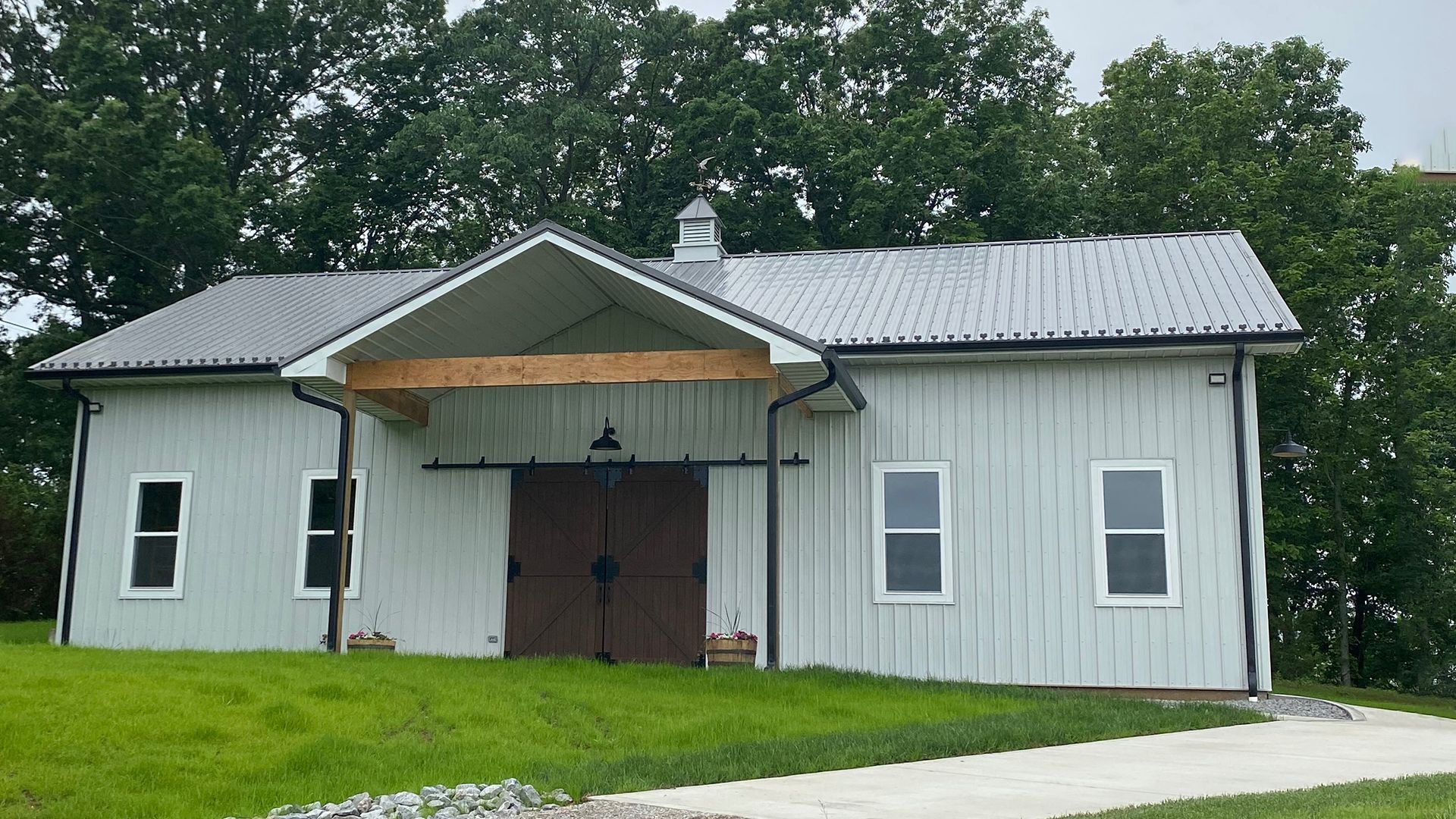 A white house with a gray roof is sitting on top of a lush green field.