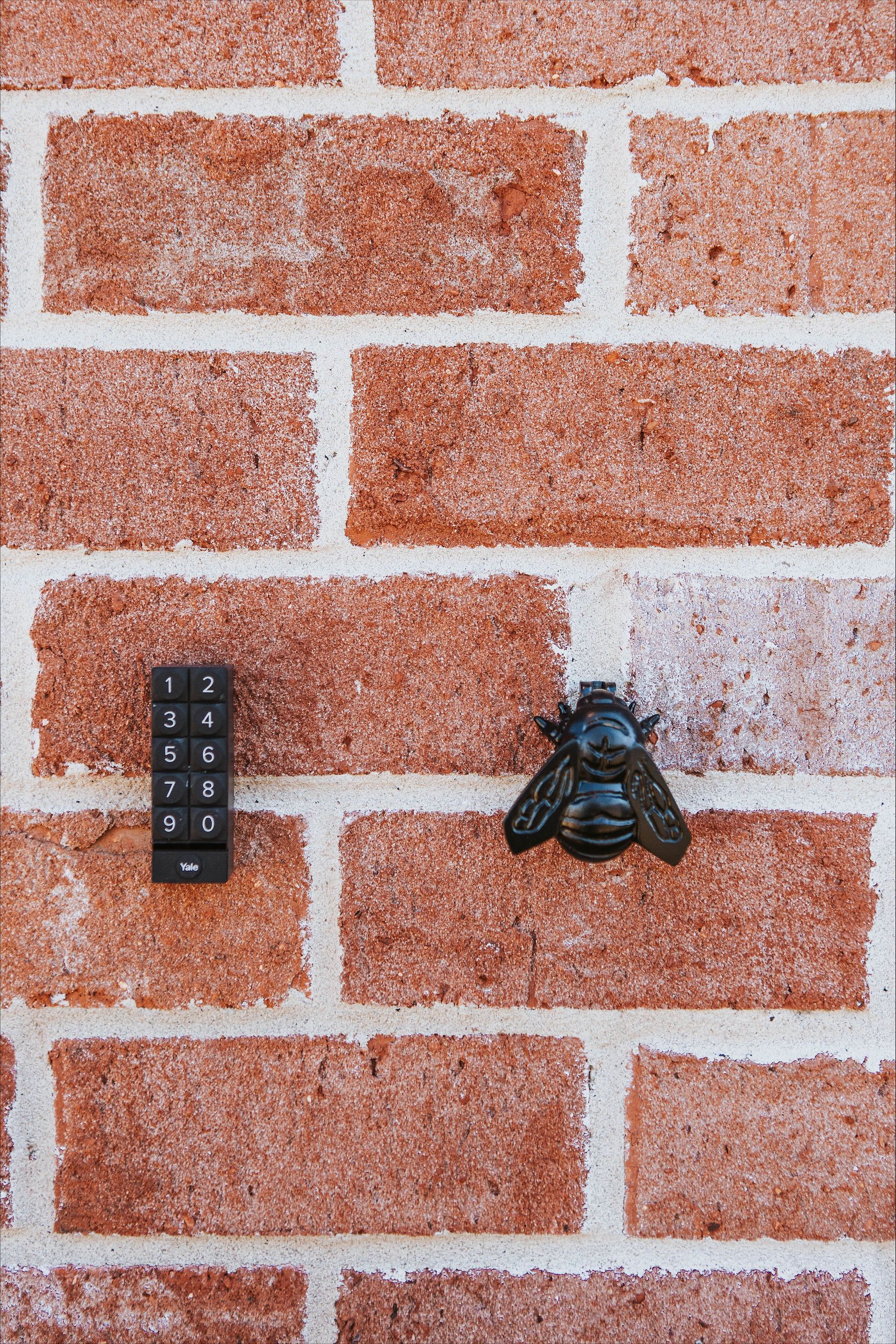 A bee is sitting on a brick wall next to a remote control.