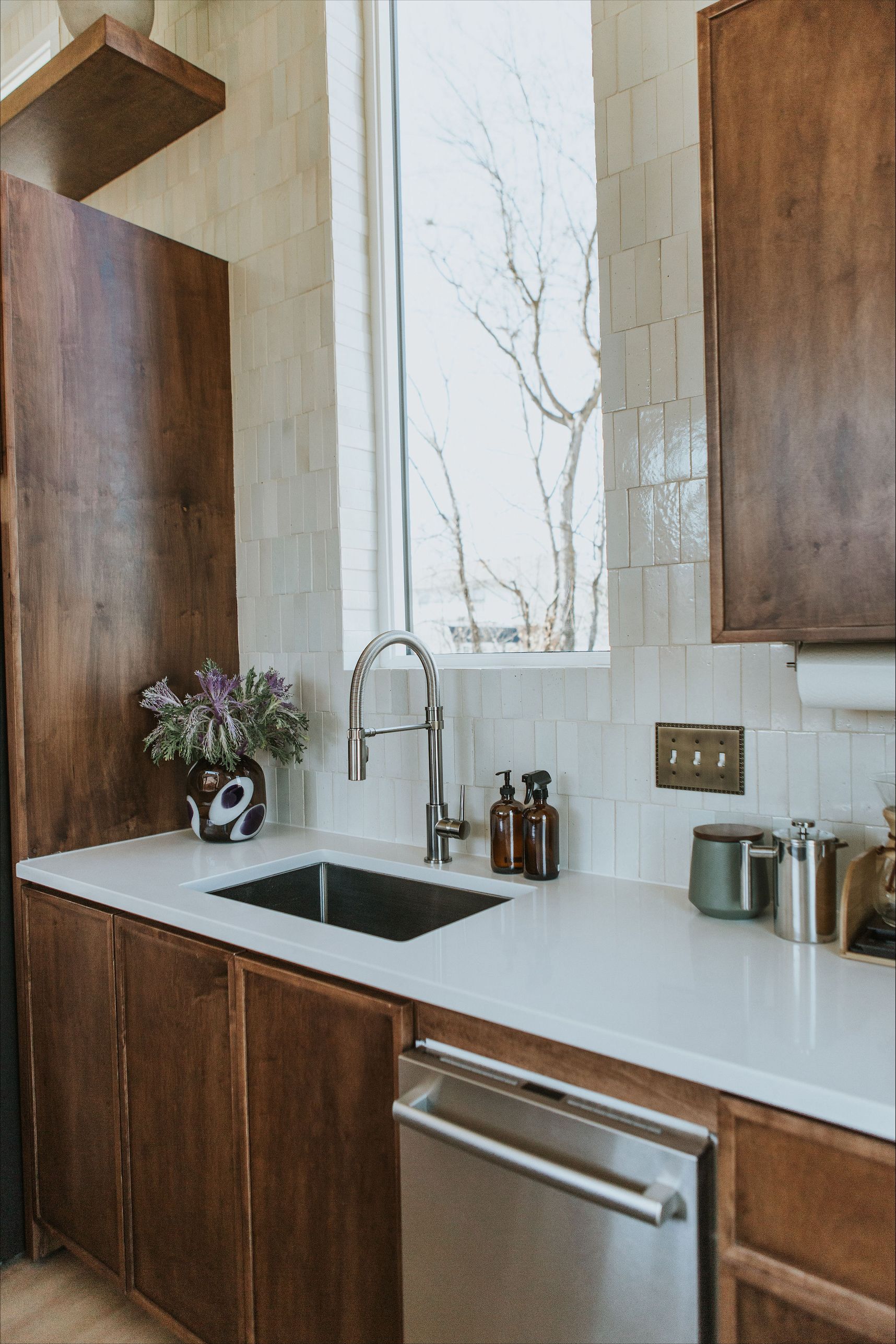 A kitchen with stainless steel appliances , wooden cabinets , a sink , and a window.