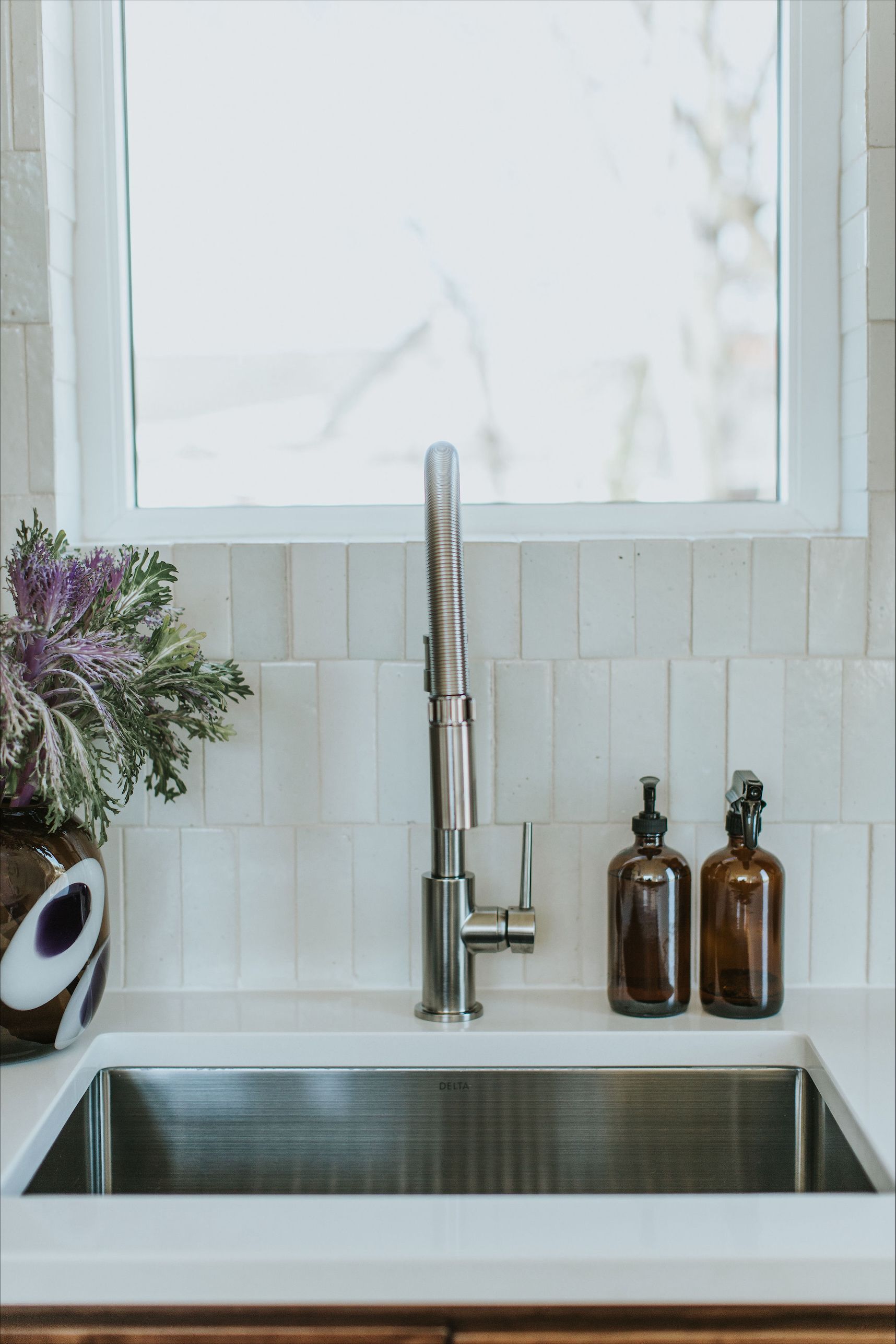 A kitchen sink with a faucet and two bottles of soap on the counter.