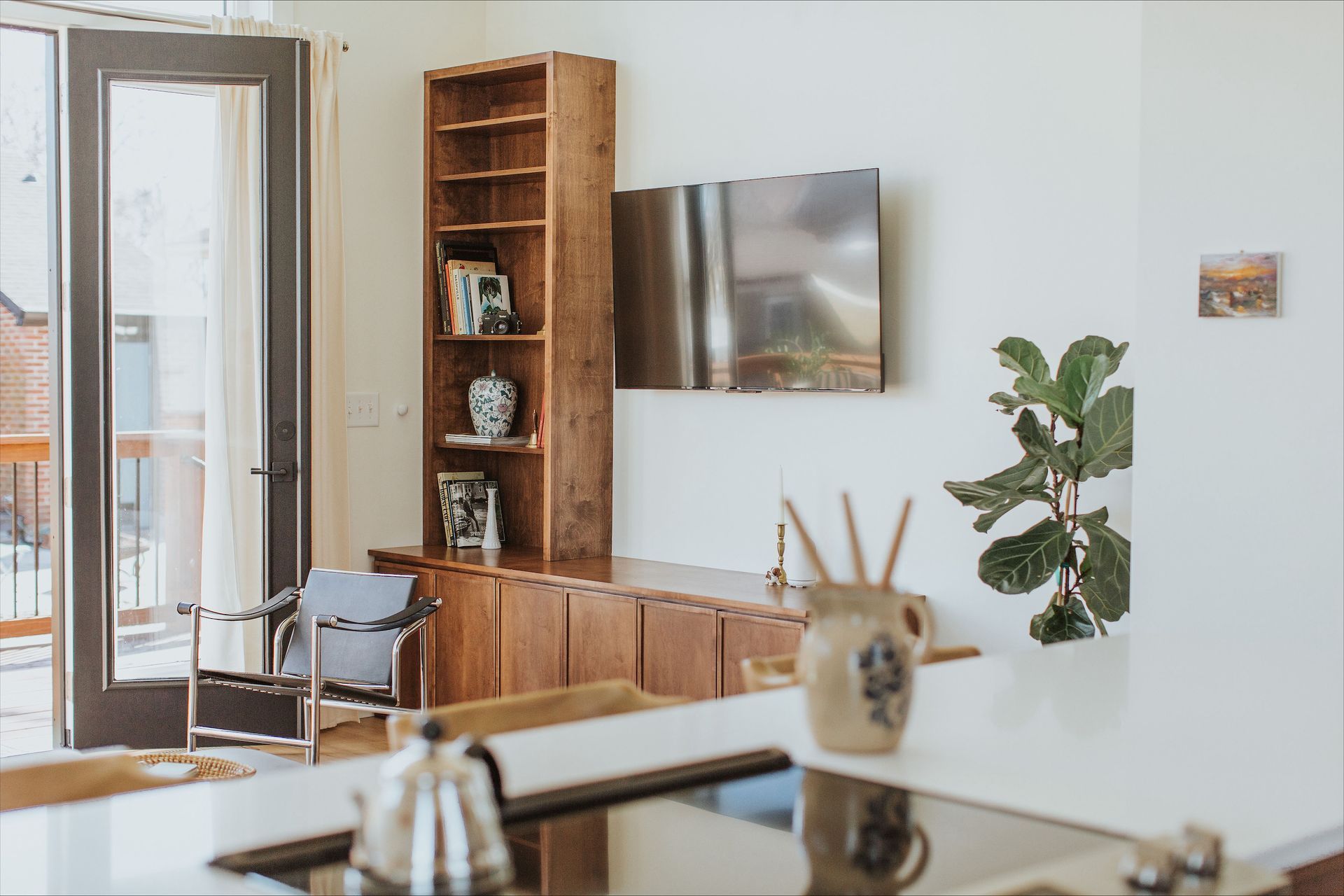 A kitchen with a stove , sink , chairs and a television on the wall.