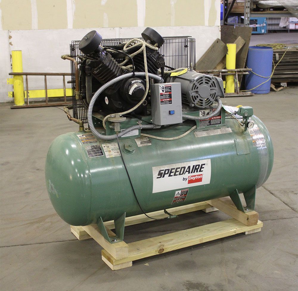 Green Speedaire air compressor on a wooden pallet in a warehouse.