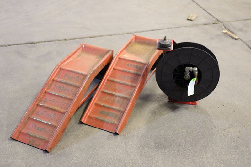 Two orange ramps and a black wire spool on a concrete surface.