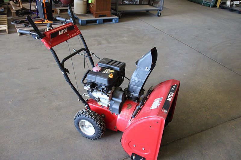 Red snow blower on a concrete floor.