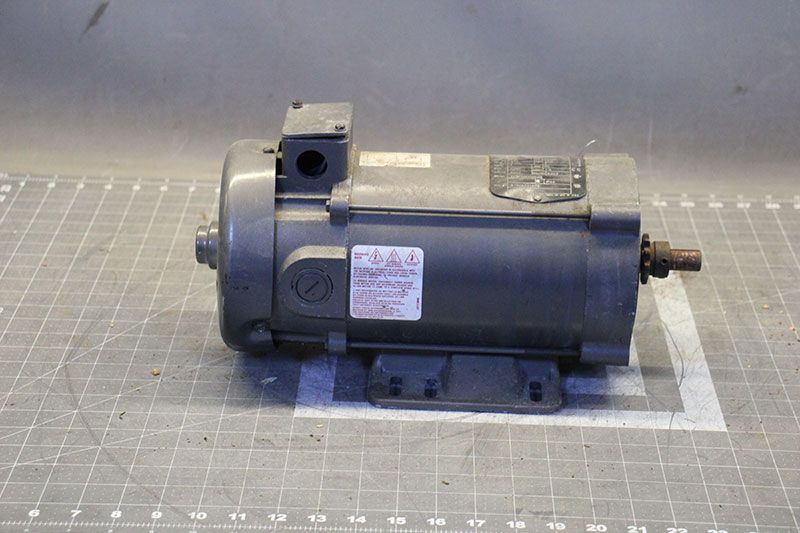 Gray electric motor with a shaft extending from the right side, mounted on a base.