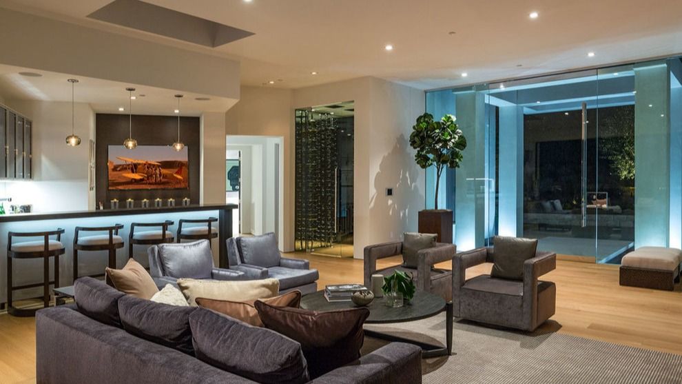 Modern living room with gray sofas, bar seating, fireplace, and large sliding glass doors to a patio