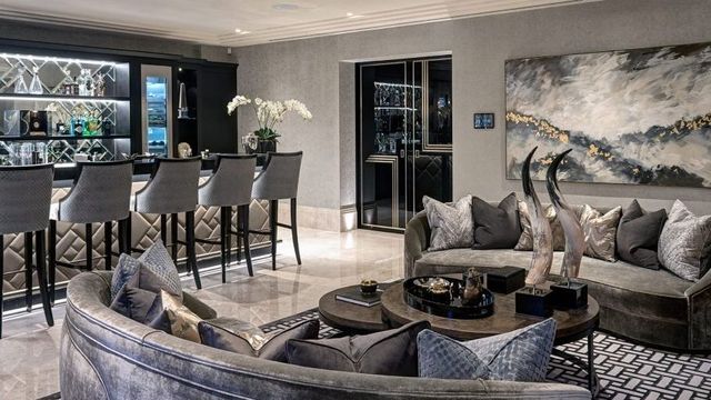 Modern luxury living room with gray sofas, round coffee table, dining area, and floor-to-ceiling windows