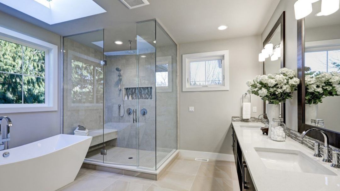 Bright modern bathroom with walk-in glass shower, bathtub, double vanity, and large window