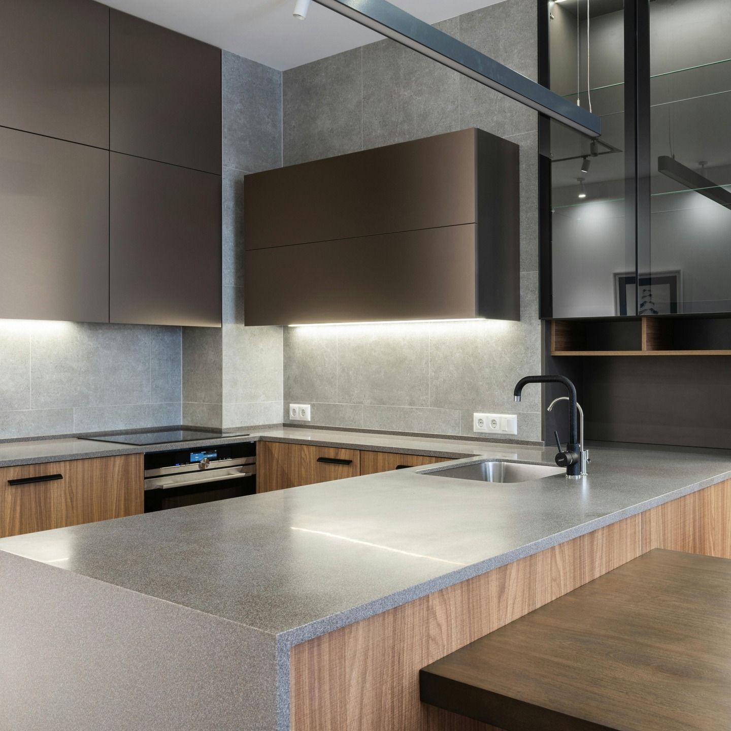 Modern kitchen with wood cabinets, gray countertops, island sink, and stainless accents